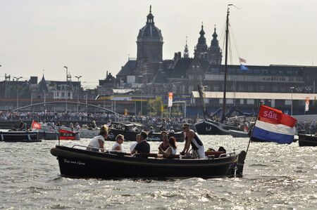 Port Amsterdam, Amsterdam, the Netherlands - August 23, 2015: Spectators in a passenger boat cruising in the Ijhaven port of Amsterdam at the time of the SAIL www.sail.nl, an international public nautical event held once in every 5 years since 1975.のeditorial素材