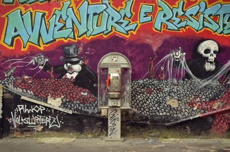 Milan, Italy - October 2, 2015: Public phone in front of a graffiti on the Via Festa Del Perdono in the city centerのeditorial素材