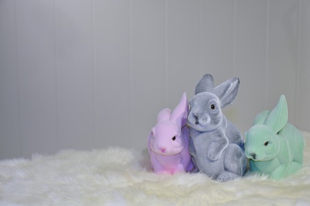 Facing view of three different colored easter bunnies on a white fur surface, in front of a light grey backgroundの写真素材