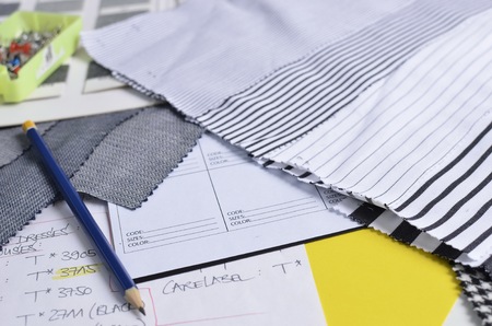 Close-up side view of a pencil, on top of a white data sheet, in the company of striped fabric...