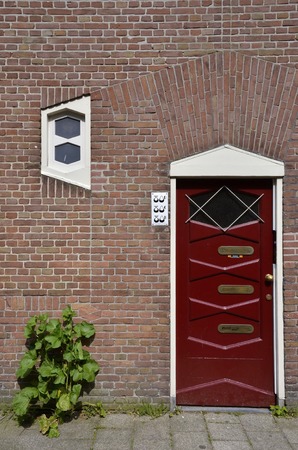 Amsterdam, Netherlands - May 21, 2016: Single red residential building entrance door, in Amsterdam School architecture style, in the Spaarndammerbuurt district.のeditorial素材