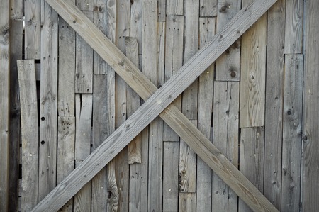 A light wood cross (X shape) on top of a light wood background (wall).の写真素材