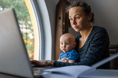 Beautiful young business woman working with her child on the computer at home.