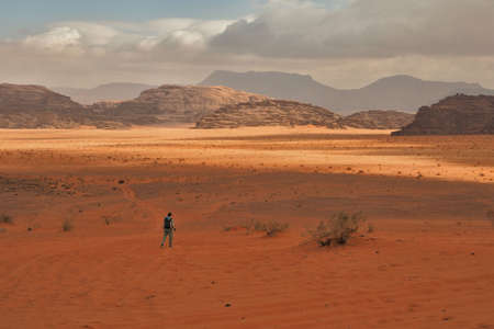 A beautiful young mom with her infant daughter in a baby carrier walking through the desert. Wadi Rum, Jordan.の写真素材