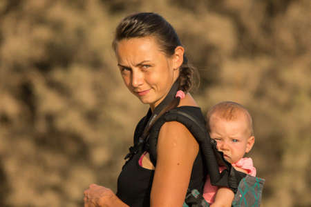 A beautiful young mom with an infant daughter in a baby carrier.