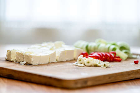 Cheese, leek, chili pepper, and garlic on a chopping board.の写真素材
