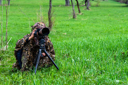 A female nature photographer waiting hidden for an animal.