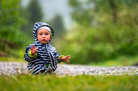 One year old baby playing in the rain.の写真素材