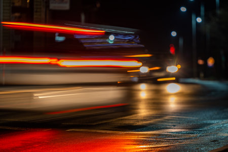 City street night blurred background. Cars approaching a pedestrian crossing. Bokeh night city life....