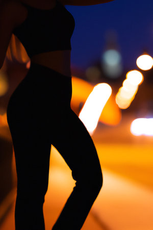 Blurred background with a silhouette of an attractive young woman standing in the street.の素材