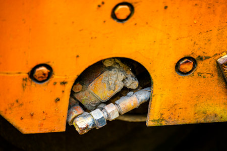 Authentic old style industrial background. Close-up of a dirty part of an old road roller. Orange colored metal.の写真素材