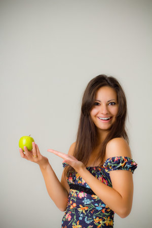 Smiling woman holding the green apple in studioの写真素材