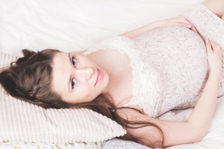 Smiling pregnant woman lying on the bed の写真素材