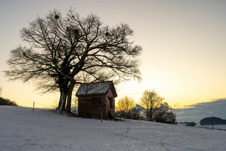 a small hut in the mountains with a snowy foreground and a nice sunriseの写真素材