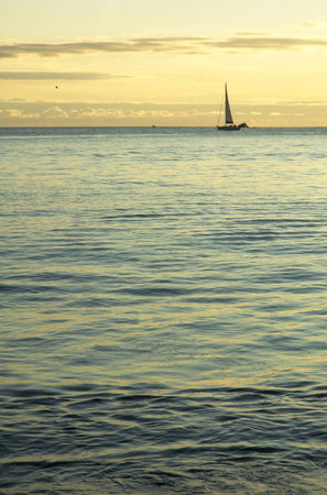 Small sail boat at cruising by sunset