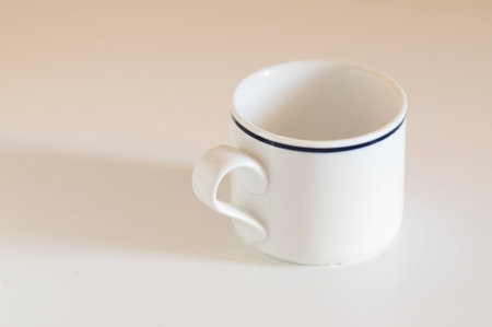 White tea cup with blue rim on white tableの写真素材