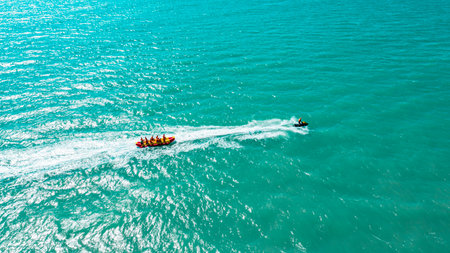 a group of people having a rest together ride an inflatable rubber banana tied to a boatの写真素材