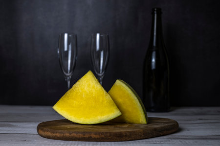 bright juicy yellow watermelon lies on the board, and next to a bottle of wine with glasses, romantic eveningの写真素材