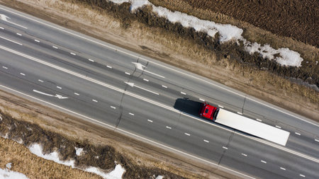 a lone truck on a spring road carrying cargo to a customer, top viewの写真素材