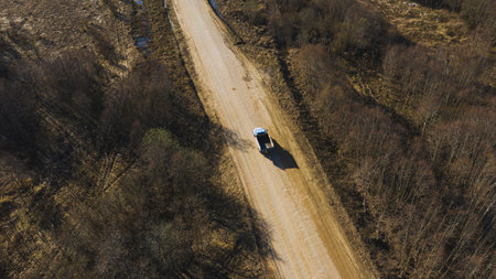 Aerial view of an old truck on a dirt road among a grassy spring dry fieldの写真素材