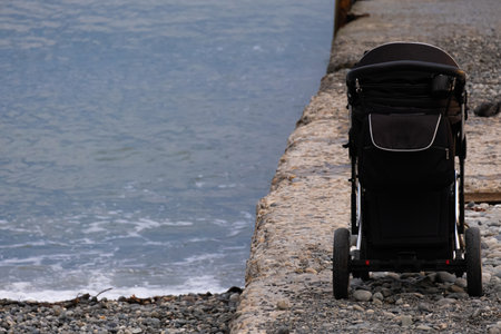 A baby stroller stands on the shore of the beach. The child fell asleep in the stroller to the sound of the waves.の写真素材