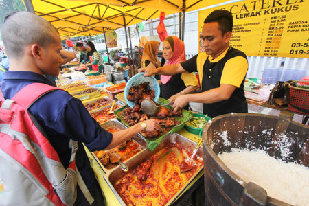 A nasi lemak hawker tends his stall in a ramadhan bazaar