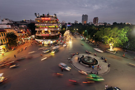 Busy streets at Hoan Kiem Lake in Hanoi with light trails from passing vehicles.のeditorial素材