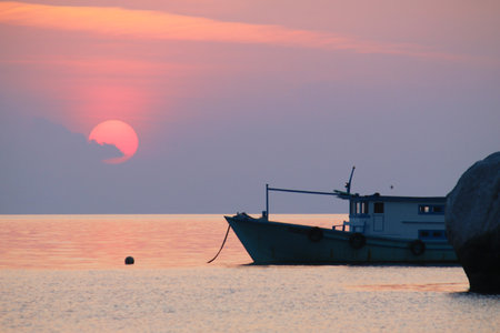 Silhouette of boat with sunset in backgroundの写真素材