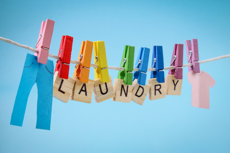 Colorful wooden pegs with LAUNDRY note against blue backgroundの写真素材