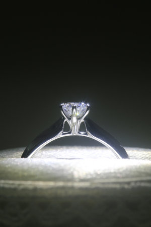 Diamond ring in holder with light focus against black background