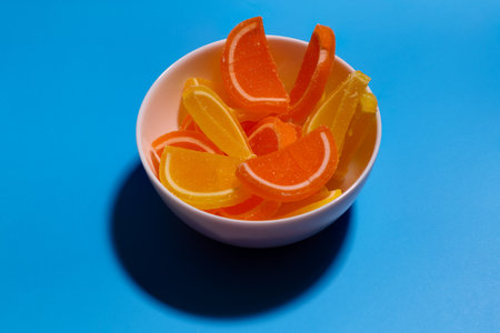 Marmalade slices of lemon and orange in white cup on blue bacground