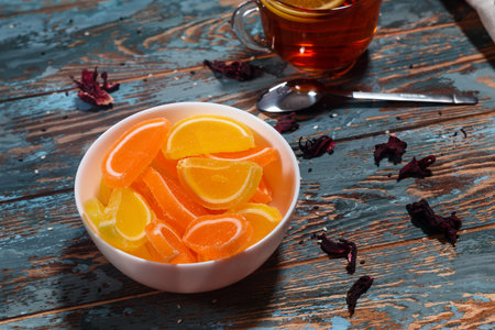 Tea cup and fruit jelly marmalade slices of lemon and orange on a wood rustic table