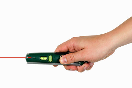 Hand of a craftsman holding green laser leveling tool with laser beam