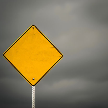 Blank yellow road sign on dark cloudy sky background. Copy space.の素材