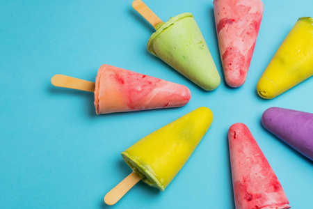 Colorful popsicles on blue background. Top view, flat lay