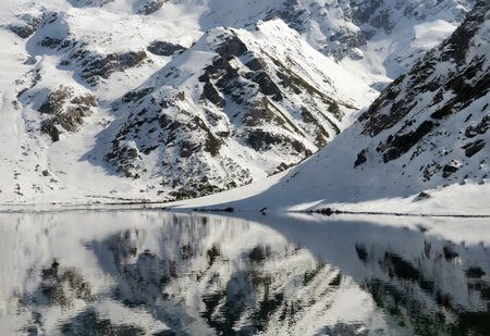Snowy mountains reflected in the water of a mountain lake, Austriaの写真素材