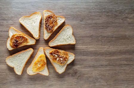 Slices of bread with apricot jam on wooden backgroundの写真素材