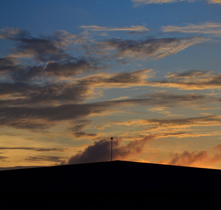 Landscape of sunrise with orange sky and the silhouette of a small factory の写真素材