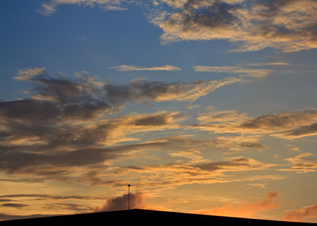 Landscape of sunrise with orange sky and the silhouette of a small factory の写真素材