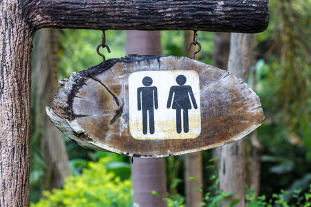 A wooden sign hung over the entrance to a toiletの写真素材