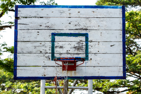 An old basketball backboard and rim under blue sky