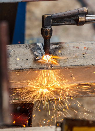 Welder in workshop manufacturing metal construction by cutting to shape using huge orange sparksの写真素材