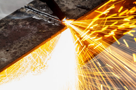 Welder in workshop manufacturing metal construction by cutting to shape using huge orange sparksの写真素材