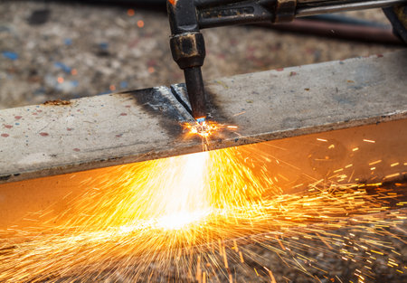 Welder in workshop manufacturing metal construction by cutting to shape using huge orange sparksの写真素材