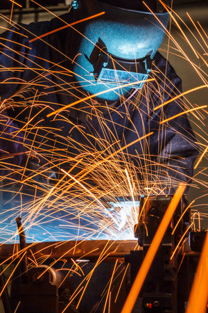 welder is welding steel structure with all safety equipment in factory