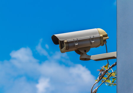 Security video camera on blue sky background.