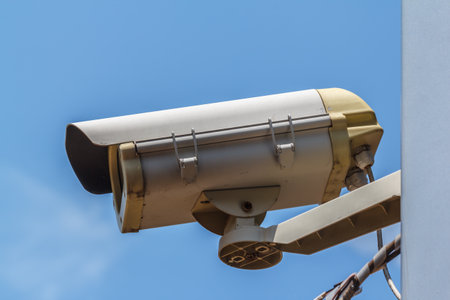 Security video camera on blue sky background.