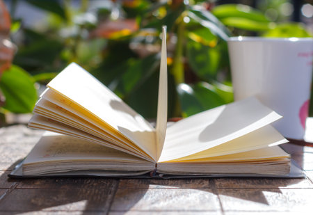 Pages of a book curved on wooden table and coffee.の写真素材