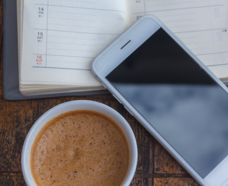 The Coffee with a phone on a wooden deskの写真素材