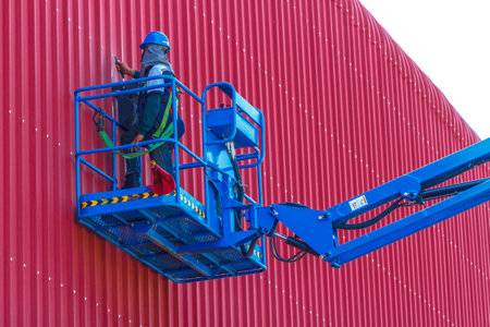 Electricians are adjusting the light bulbs at the height of the factory.の写真素材